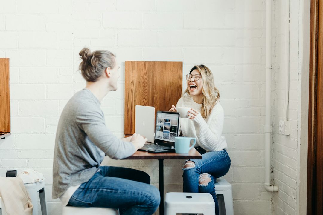 Two people having a relaxed conversation over coffee in a modern office lounge